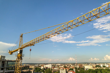 Fototapeta na wymiar Apartment or office tall building under construction. Brick walls, glass windows, scaffolding and concrete support pillars. Tower crane on bright blue sky copy space background.