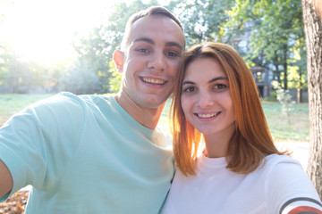Obraz premium Happy young couple taking selfie outdoors in warm sunny weather.