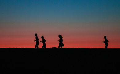 Fototapeta na wymiar two girls running around the city marathon at sunset