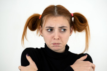 Closeup portrait of a sad redhead teenage girl with childish hairstyle looking offended isolated on...