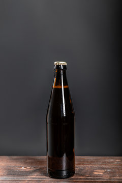 bottle with beer on a wooden table on a dark background