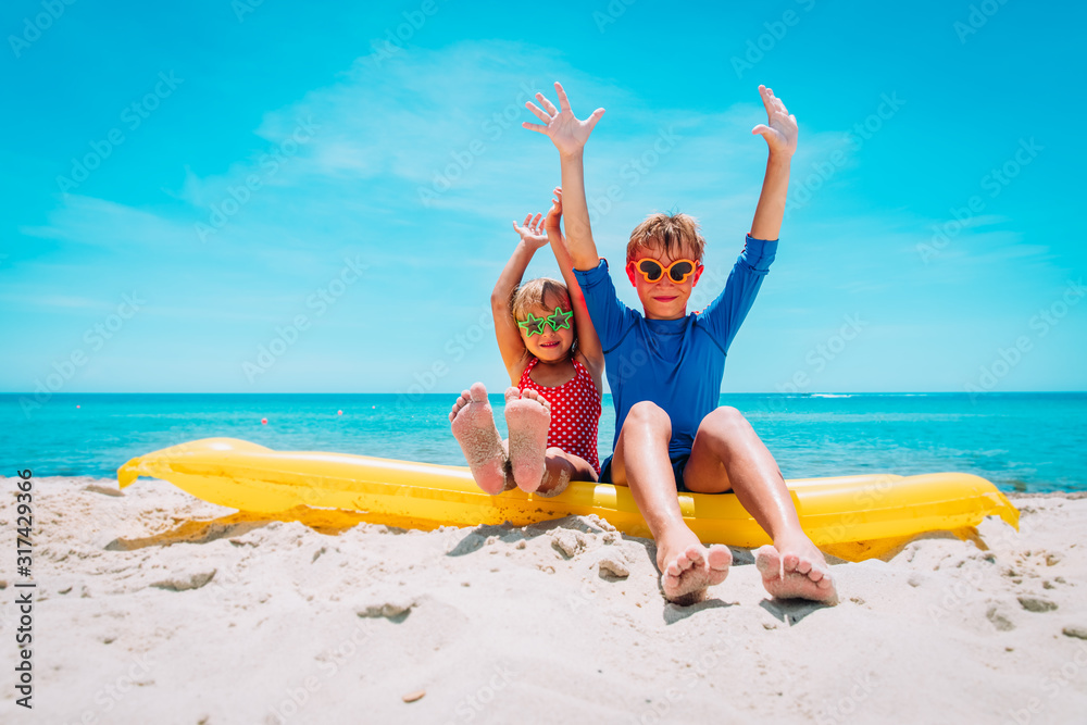 Poster happy cute boy and girl with floatie on beach vacation