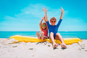 happy cute boy and girl with floatie on beach vacation