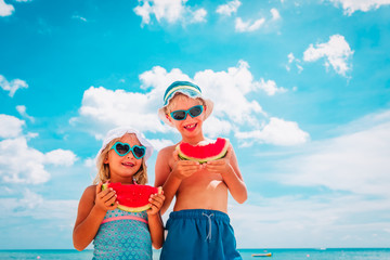 happy boy and girl eating watermelon at beach - 317429514