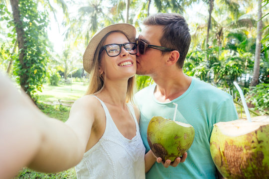 Young loving couple drink coconut taking selfie pictures photo on camera smatrphone
