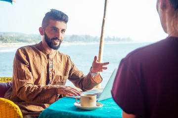 Egyptian man foreign language teacher teaching female student at tropical cafe