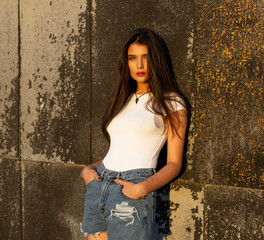 Beauty woman portrait. Close-up portrait of beautiful young adult woman in the sunlight at sunset, looking at camera, wear in white shirt and denim.