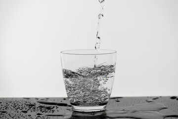 Motion blur of pouring pure drinking water flow into the glass making splash of clearly bubble