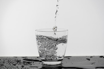 Motion blur of pouring pure drinking water flow into the glass making splash of clearly bubble