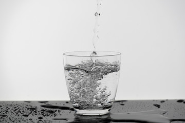Motion blur of pouring pure drinking water flow into the glass making splash of clearly bubble