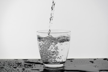 Motion blur of pouring pure drinking water flow into the glass making splash of clearly bubble