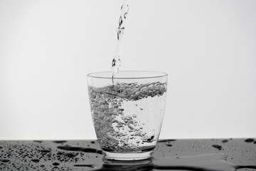 Motion blur of pouring pure drinking water flow into the glass making splash of clearly bubble