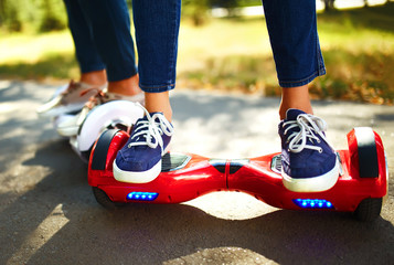 Legs of man and woman riding on the Hoverboard for relaxing time together outdoor at the city. A young couple riding a hoverboard in a park, self-balancing scooter. Active lifestyle technology future.