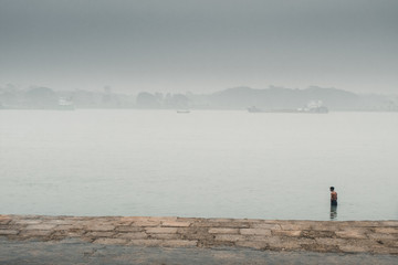 Fototapeta na wymiar A man standing up in river at foggy morning 