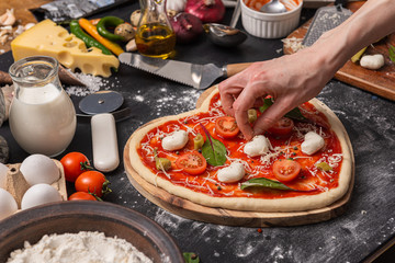 woman preparing a festive dinner for two in honor of Valentine's Day classic Italian pizza...