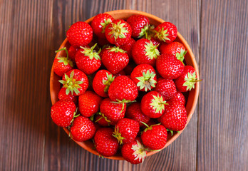 red fresh strawberries in a plate on a wooden background