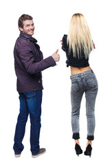 Back view of couple couple in winter jackets showing thumbs up.