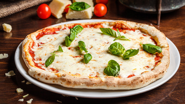 talian Cuisine. Classic Italian pizza Margherita with basil, cheese and tomatoes. Serving dishes in a restaurant on a white plate. background image, copy space text