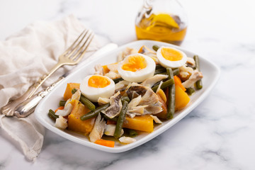 cod fish with sweet potato and olives on dish on ceramic background