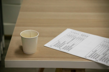 Blank paper coffee mugs resting on a wooden table complete with documents.