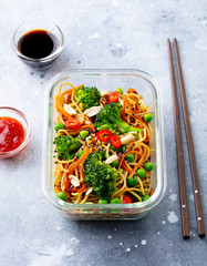 Stir fry noodles, udon with vegetables in lunch box. Grey stone background.