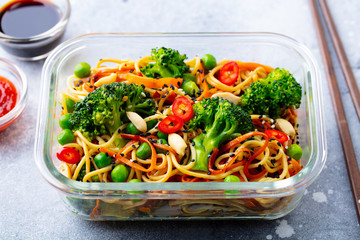 Stir fry noodles, udon with vegetables in lunch box. Grey stone background. Close up.