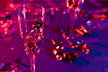Champagne glasses with party tinsel on bright background