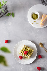 Tiramisu cake with matcha green tea and raspberries on gray concrete background. Top view. Menu, confectionery, cafe concept