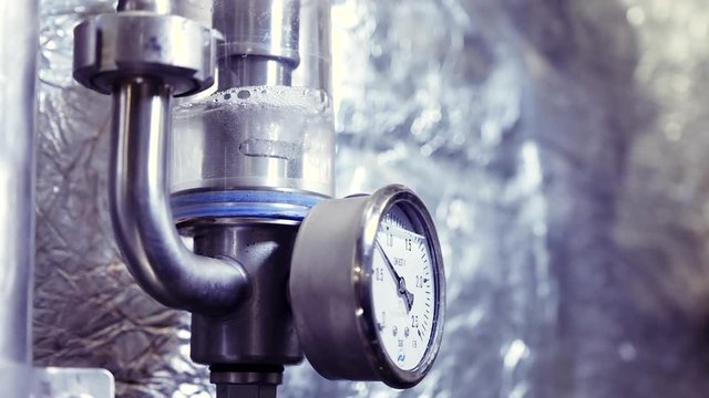 Operating pressure gauge mounted on a beer fermentation tank. Air bubbles in a glass flask.