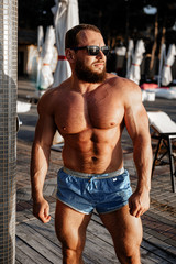 Obraz premium Muscular man bodybuilder tanning in a beach club