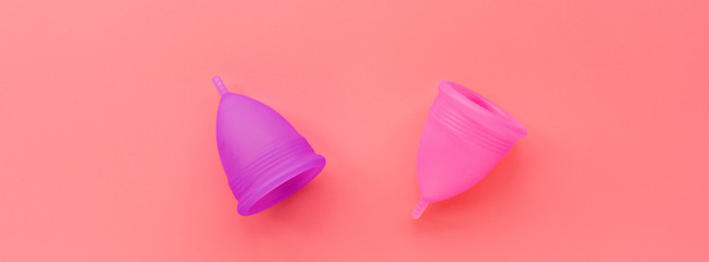 Menstrual cups on pink background. Alternative feminine hygiene product during the period. Women health concept. Copy space. Eco friendly concept, zero waste product. Flat lay, mockup, template