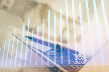 Stock market graph on background with desk and personal computer. Double exposure. Concept of financial analysis.