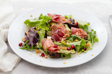 salad prosciutto with pomegranate on white plate