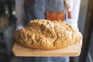 A waitress holding and serving a loaf of whole grain bread