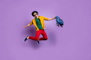 Fototapeta na wymiar Full size photo of positive guy jump hold hands like bird fly hold blue backpack wear casual modern outfit isolated over purple color background