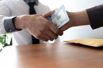 Two businessman making handshake and receiving a bribe in the office room.