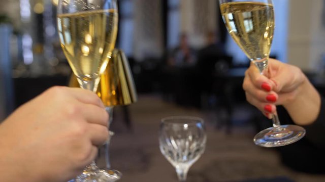 A couple toasting with champagne in a luxurious restaurant in intimate atmosphere. Close up slow motion shot.