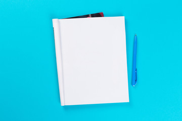 top view of empty open notebook on blue background, office equipment, school supplies and education concept