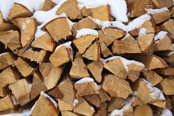 Chopped firewood in a woodpile. Snow lies on chopped wood. Background, wood fuel.