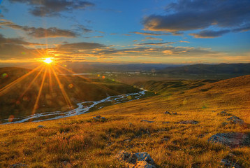 Sunset. Sunny evening. Alpine hills and mountains. orange light. Mountain rivers and lakes. Ukok Plateau.