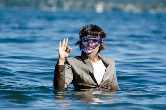 Business Woman With Suit And Diving Mask In The Water And Showing OK Signal.