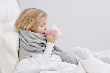 little sick girl drinking from a mug