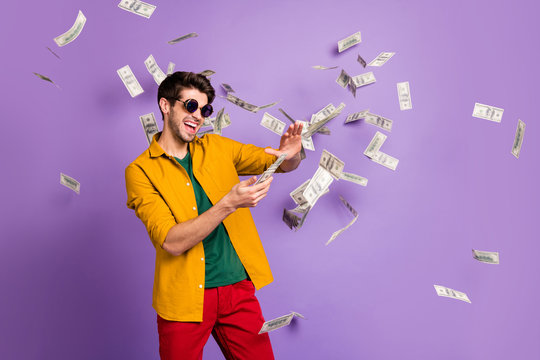 Photo of white cheerful brown haired trendy casual man with bristle throwing cash with crazy emotions on face in red pants yellow shirt isolated violet pastel color background