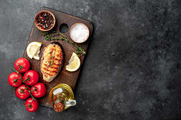 Grilled salmon steak with spices and tomatoes on a stone background with copy space for your text.