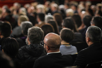 People in the audience watching a classical concert inside a hall.