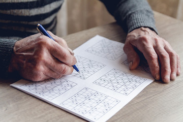 Senior solves sudoku or a crossword puzzle to slow the progressi