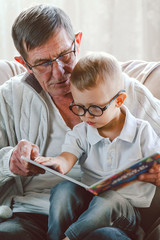 Grandfather and grandson are reading a book