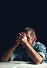 Depressed senior covers his face with his hands. Alzheimer's disease concept.