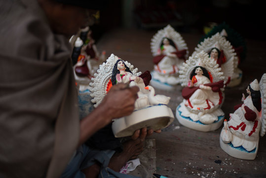 An Indian artist making and painting clay idols of Hindu Goddess Saraswati for the Indian Bengali festival in winter in Bengal. Indian culture and religion.