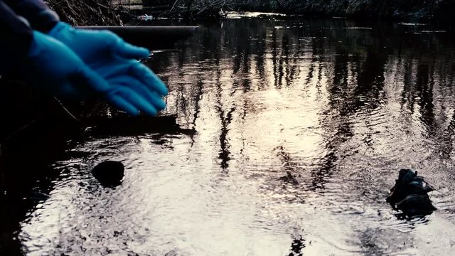 Water sample. Hand in glove preparing to  collects water from a river. Test water. 